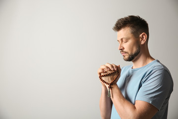 Religious man praying on light background