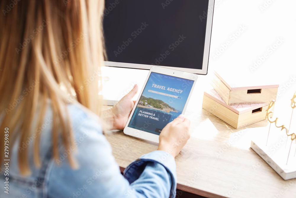 Woman with tablet computer visiting travel agency website at home