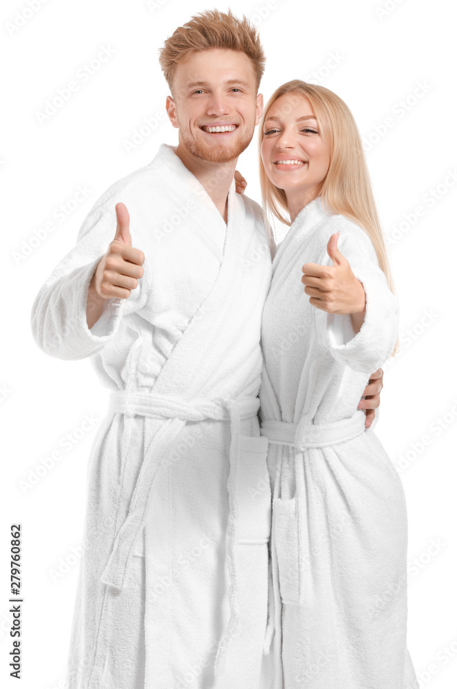 Happy young couple in bathrobes showing thumb-up on white background