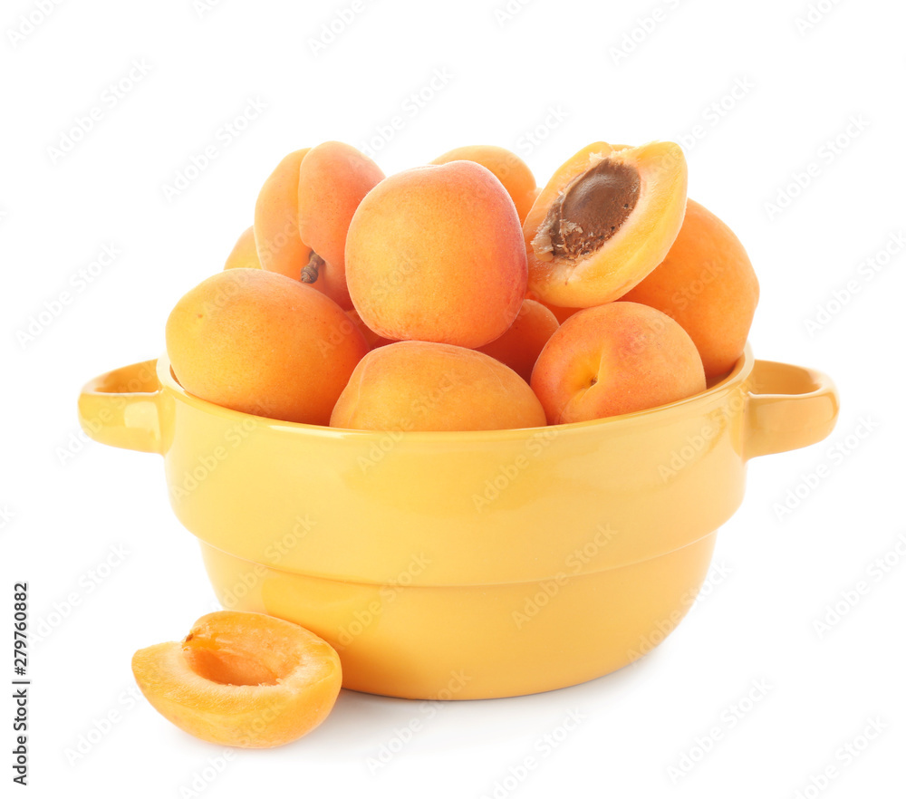 Pot with tasty ripe apricots on white background