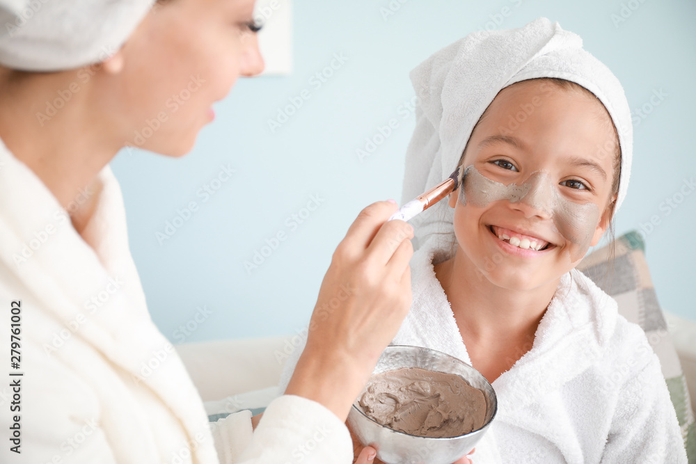 Mother applying mask onto daughter's face at home