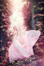 Beauty Romantic Young Woman In Long Chiffon Dress With Gown Posing In Fantasy Misty Forest. Beautiful Happy Bride Model Girl Enjoying Nature Outdoors