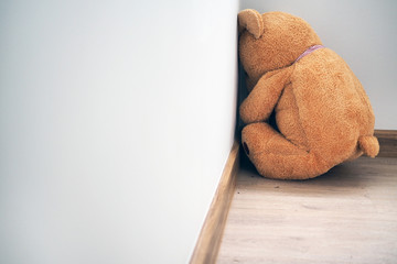 child concept of sorrow. teddy bear sitting leaning against the wall of the house alone, look sad an