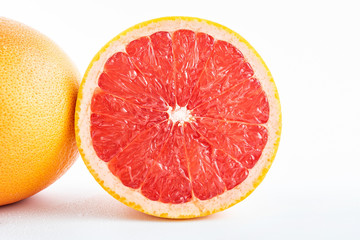 Fresh grapefruit and cut red flesh on white background