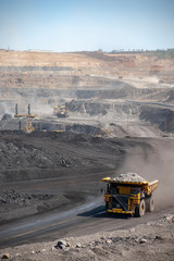 Wall Mural - Big yellow mining truck hauling rock in dusty coal mine