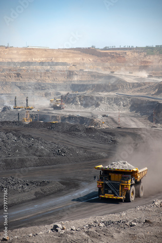 Big yellow mining truck hauling rock in dusty coal mine