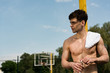 © LIGHTFIELD STUDIOS - sexy shirtless sportsman with towel opening bottle of water at basketball court