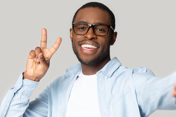 Wall Mural - Smiling black man in glasses make selfie on gadget