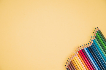 Arrangement of colorful pencils at the corner of yellow backdrop