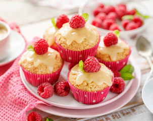 Wall Mural - Cupcakes with white chocolate and fresh raspberries on a ceramic plate on a wooden white table.  A delicious dessert or breakfast.