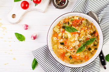 Wall Mural - Minestrone, italian vegetable soup with pasta on white table. Vegan soup.  Top view