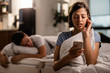 © Drazen - Young woman reading text message on smart phone in the bedroom.