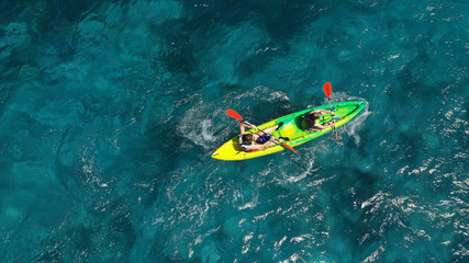 Wall Mural - Aerial drone photo of fit couple practising on a colourful canoe in turquoise open ocean bay with crystal clear sea