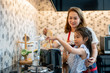 © iammotos - happy Mother teaching daughter making breakfast toast bread with toaster at home kitchen together . loving family.  child girl excited looking Mom cooking indoors