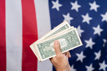 Hand Holding Dollar With America Flag Background