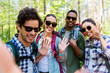 © Syda Productions - travel, tourism, hike and people concept - group of friends with backpacks taking selfie and waving hands in forest