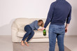 © satura_ - People, violence and abuse concept - Man drinking alcohol while wife is lying on sofa