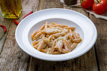 Wall Mural - Penne four cheese on white plate on wooden table