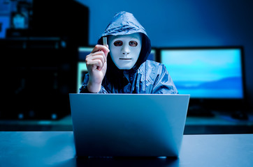 Anonymous computer hacker in white mask and hoodie. Obscured dark face holds a USB flash drive in his hands, Data thief, internet attack, darknet and cyber security concept, with copy space