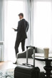 © Drobot Dean - Image of caucasian young man standing by window in hotel apartment during business trip