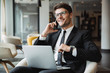 © Drobot Dean - Portrait of happy young businessman using laptop computer and talking on smartphone in hotel hall