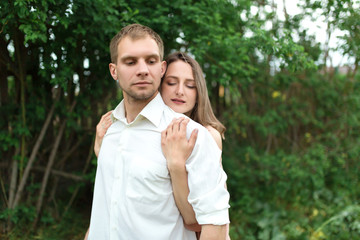 Young loving couple hugging and dancing on the green grass on the lawn. Beautiful and happy woman and man gently touch each other. Beautiful couple in love. girl in the dress and the guy in the shirt