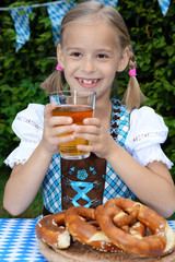 Wall Mural - Blond girl in dirndl for Oktoberfest in Bavaria drinks Apple Juice