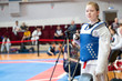 © borisblik - a girl participating in Taekwondo competitions in a blue protective vest on the background of Taekwondo competitions close-up