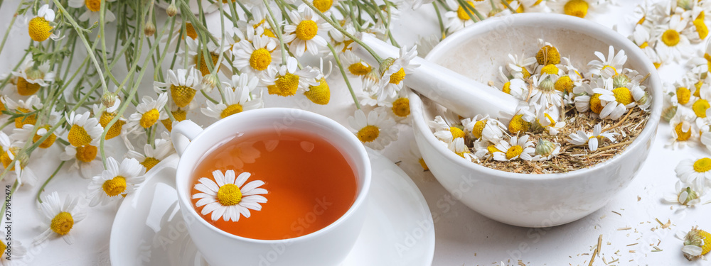 Rural still-life - cup of brewed chamomile tea on the background of a bouquet of daisies, closeup - obrazy, fototapety, plakaty 