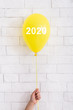 © Prostock-studio - Yellow bright balloon with 2020 white text in woman hand