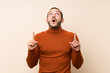 © luismolinero - Colombian man with turtleneck sweater surprised and pointing up