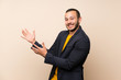 © luismolinero - Colombian man over isolated background extending hands to the side for inviting to come