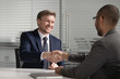 © fizkes - Happy diverse businessmen shake hands make business agreement at meeting