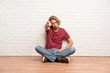 © luismolinero - Blonde man sitting on the floor showing thumb down with negative expression