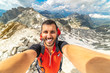 Hiker taking a selfie while out trekking in the wilderness. trekking man at the top of a pass making selfie against snow capped mountains in Alps. 