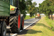 Ciągmik rolniczy, traktor i kombajn na drodze asfaltowej w słoneczny dzień.