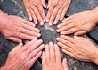 a group of hands touch to formalize their friendship. Caucasian people women and men. Dark wooden table on background