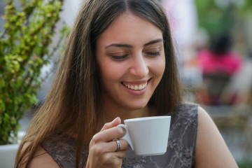 Wall Mural - Portrait of a young beautiful woman sitting in a cafe outdoor drinking coffee	