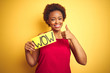 © Krakenimages.com - Young african american woman showing wow banner board over yellow isolated background happy with big smile doing ok sign, thumb up with fingers, excellent sign