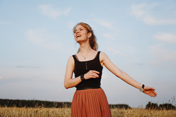 Happy young woman enjoying nature and sunlight in straw field