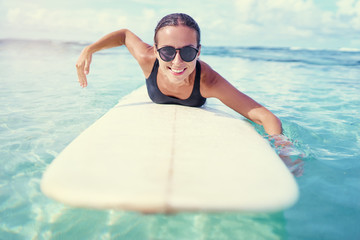 Portrait of surfer woman surfing having fun on Siargao Beach, Philippines. Female girl laughing on surfboard smiling happy living healthy lifestyle.