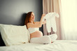 © luengo_ua - Happy healthy pragnancy. Young pregnant  woman sittng in bedroom at home holding baby's cloth.