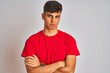 © Krakenimages.com - Young indian man wearing red t-shirt standing over isolated white background skeptic and nervous, disapproving expression on face with crossed arms. Negative person.