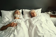 © luengo_ua - Senior family couple sleeping together in bed.