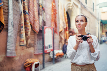 Wall Mural - Tourism and technology. Happy young woman taking photo of  Marrakesh old town. Traveling by Morocco.