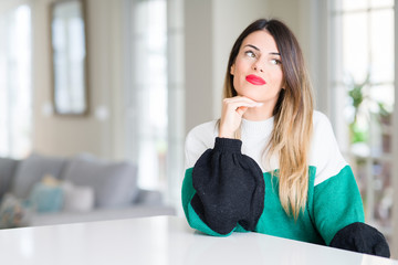 Canvas Print - Young beautiful woman wearing winter sweater at home with hand on chin thinking about question, pensive expression. Smiling with thoughtful face. Doubt concept.