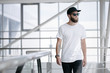 © 4Max - Hipster handsome male model with beard wearing white blank t-shirt and a baseball cap with space for your logo or design in casual urban style