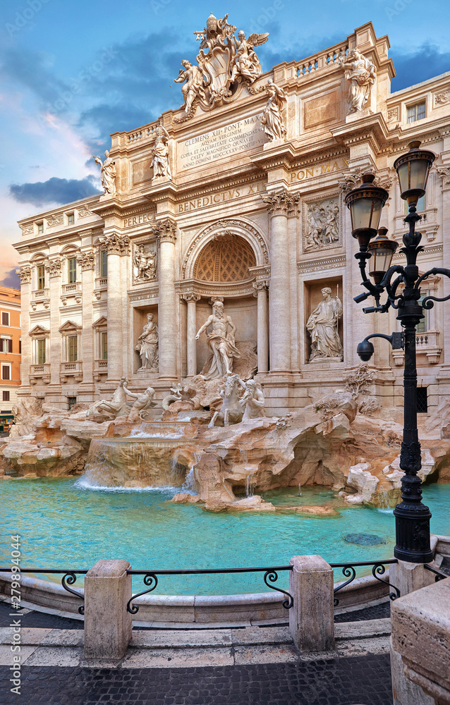 Trevi Fountain in Rome, Italy. Ancient fountain. Roman statues at piazza in old medieval city among traditional italian houses and street lamps. Famous landmark. Touristic destination for vacation.