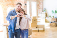 Beautiful Young Couple Moving To A New House Smiling In Love Showing Heart Symbol And Shape With Hands. Romantic Concept.