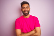 © Krakenimages.com - Young indian man wearing t-shirt standing over isolated pink background happy face smiling with crossed arms looking at the camera. Positive person.